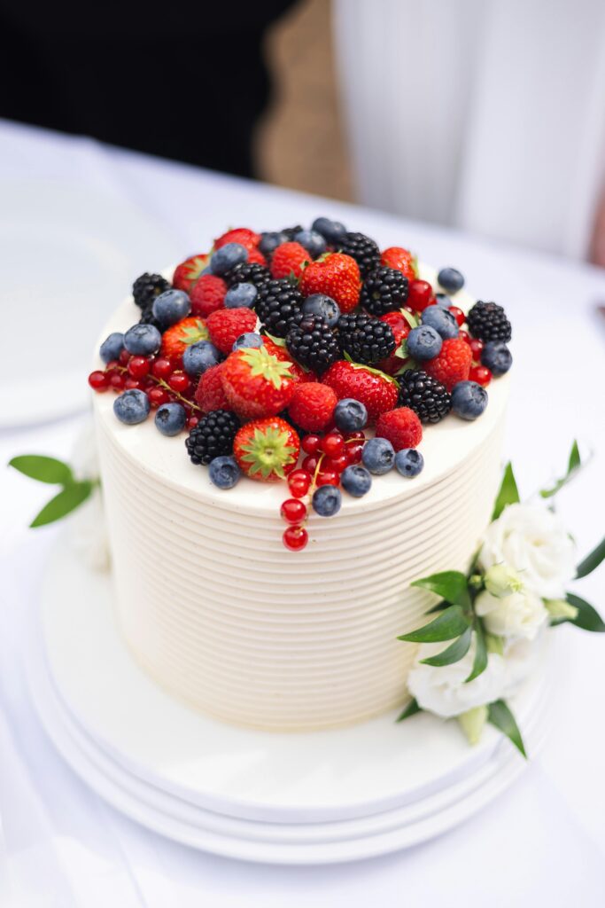 Delicious wedding cake topped with assorted fresh berries and elegant flowers for a special occasion.