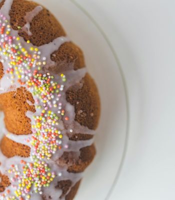 Close-up of a Bundt cake with icing and colorful sprinkles, perfect for celebrations.