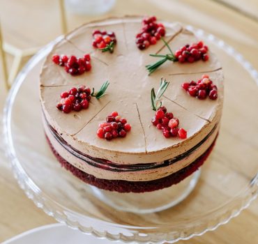 Chocolate dessert layered with cream, decorated with berries on a cake stand.